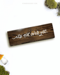 Dark brown wooden sign with 'it's not over yet' text written on it, lying on a white background