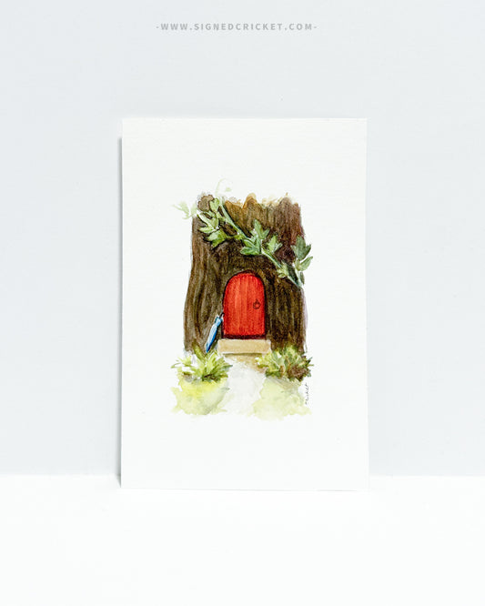 4x6 watercolor painting original featuring a miniature home in a tree stump with a bright red front door and trailing vines. At the end of the footpath, a blue umbrella leans up against the doorstep.
