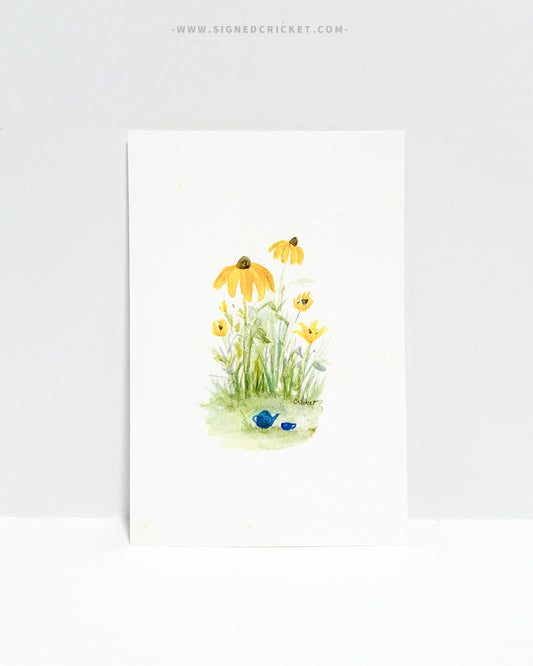 4x6 watercolor original featuring a blue tea pot and mug on the grass beneath a clump of bright yellow black-eyed Susan wildflowers